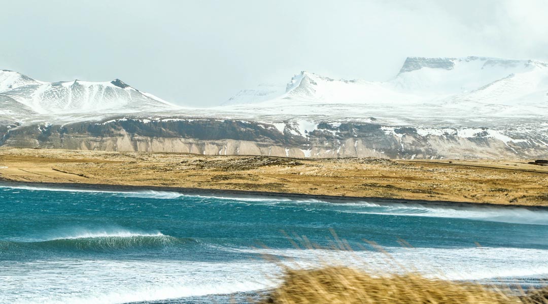 kaltwassersurfen in europa - welle vor schneebedeckten bergen in island
